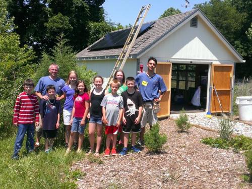 A group of people in front of house installed with solar panels